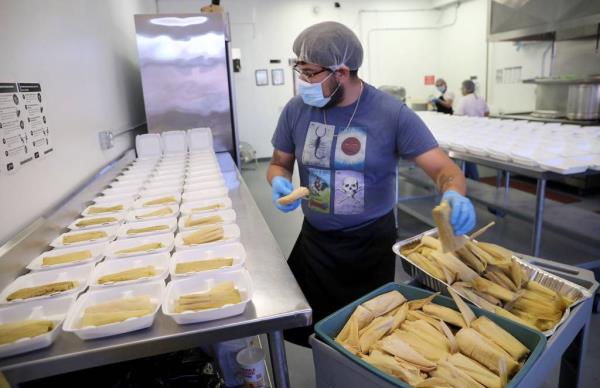 Edson Cerda places tamales into plastic co<em></em>ntainers at Cocina Compartida de Trabajadores Cooperativistas on June 17, 2021. 