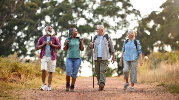 Group Of Active Senior Friends Enjoying Hiking Through Countryside Walking Along Track Together