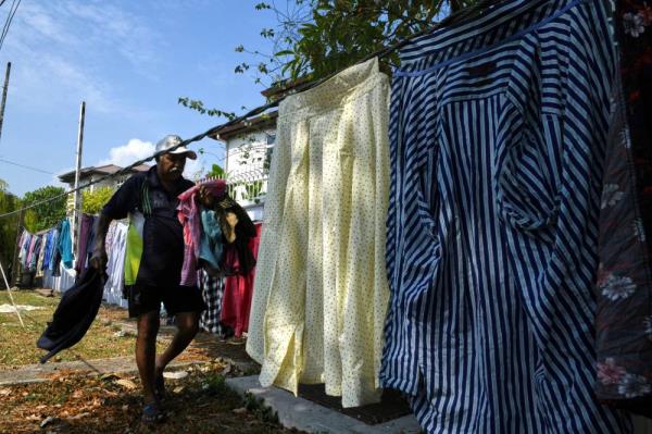 Raman Angko drying the clothes. Photo by Bernama
